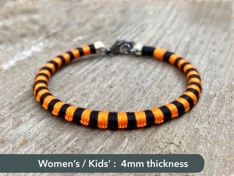 Peut inclure: Bracelet ray&eacute; noir et orange avec un fermoir argent&eacute;. Femmes / Enfants : 4 mm d'&eacute;paisseur.