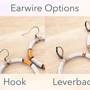 Peut inclure: Deux boucles d'oreilles cr&eacute;oles avec un motif tiss&eacute; blanc et orange. La boucle d'oreille de gauche a un fermoir crochet, et la boucle d'oreille de droite a un fermoir &agrave; levier. Options de fermoirs.