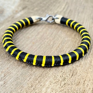 May include: A black and yellow striped bracelet with a silver clasp.
