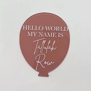 May include: A pink balloon with the text "Hello World My Name Is Tallulah Row" in white lettering.