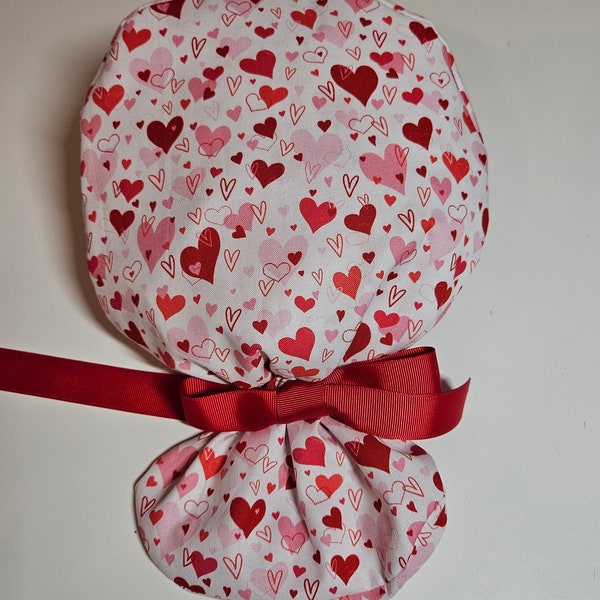 All hearts fabric lined surgical scrub cap with *New* 8" MEDIUM elastic ponytail pocket and ribbon tie. Optional face mask buttons.