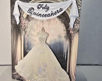 May include: A greeting card featuring a white banner with the black text Feliz Quinceañera draped over an illustration of a ballgown on a mannequin. The background depicts an arched stone entryway with floral accents and a soft, hazy forest scene.