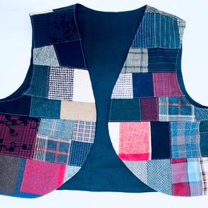May include: A patchwork vest with a teal lining. The vest is made of various fabrics in shades of blue, red, green, and brown. The vest has a curved hemline.