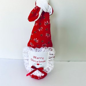 May include: A red and white Christmas stocking with a white lace trim and a white embroidered patch that says "Merry Christmas".