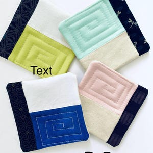Pode incluir: Quatro bases para copos quadradas de tecido em tons de verde, azul, rosa e branco. Cada base apresenta um design geom&eacute;trico e uma borda estampada contrastante. O texto "Text" e o n&uacute;mero "133" s&atilde;o vis&iacute;veis.