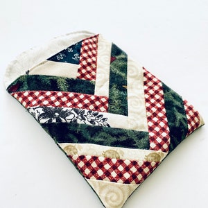 May include: A small quilted pouch with a patchwork design featuring red and white gingham, green floral fabric, and cream fabric with a swirl pattern.