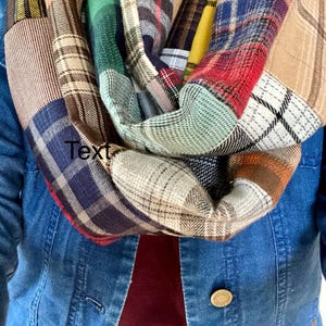 Könnte beinhalten: Ein farbenfroher karierter Infinity-Schal aus Patchwork-Stoff. Der Schal besteht aus verschiedenen Farbtönen von kariertem Stoff in Rot, Blau, Grün, Gelb und Braun.