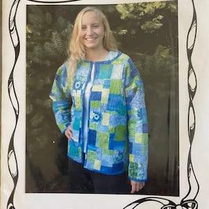 May include: A woman wearing a quilted jacket with a patchwork design in shades of blue and green. The jacket is open, revealing a white top underneath. The text "The Mystery Jacket" is at the top of the image, and "Carolyn's Creative Designs" is at the bottom.