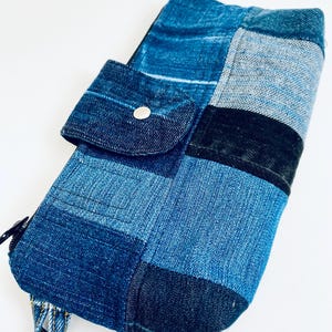 Peut inclure: Un petit sac en jean bleu patchwork avec une fermeture éclair et une petite poche sur le devant. Le sac a une bandoulière en jean.