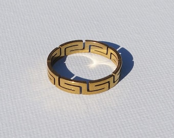 Può includere: Un anello d'oro con un designo a chiave greca.