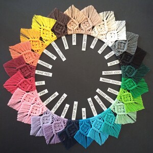 May include: A color wheel of 20 different colors of macrame tassel wall hangings. The colors are arranged in a circle, starting with beige, cube red, khaki, brown, light yellow, yellow, orange, wine red, red, pink, light pink, light purple, purple, deep blue, blue, light blue, lake blue, light green, green, grass green, deep green, black, and grey.
