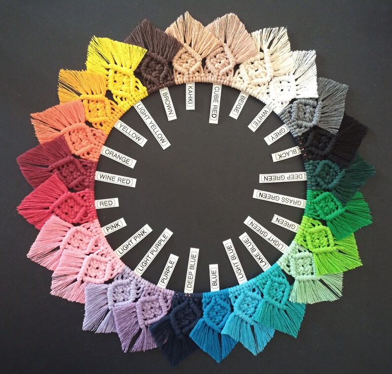 May include: A color wheel of 20 different colors of macrame tassel wall hangings. The colors are arranged in a circle, starting with beige, cube red, khaki, brown, light yellow, yellow, orange, wine red, red, pink, light pink, light purple, purple, deep blue, blue, light blue, lake blue, light green, green, grass green, deep green, black, and grey.