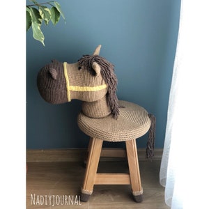 May include: A brown crocheted horse rocking chair with a wooden base. The horse has a yellow and brown saddle and a long brown mane.