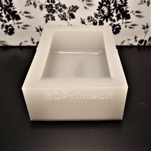 Puede incluir: Molde de silicona rectangular blanco con una superficie lisa y una inscripción "3D Printed" en relieve en la parte inferior.