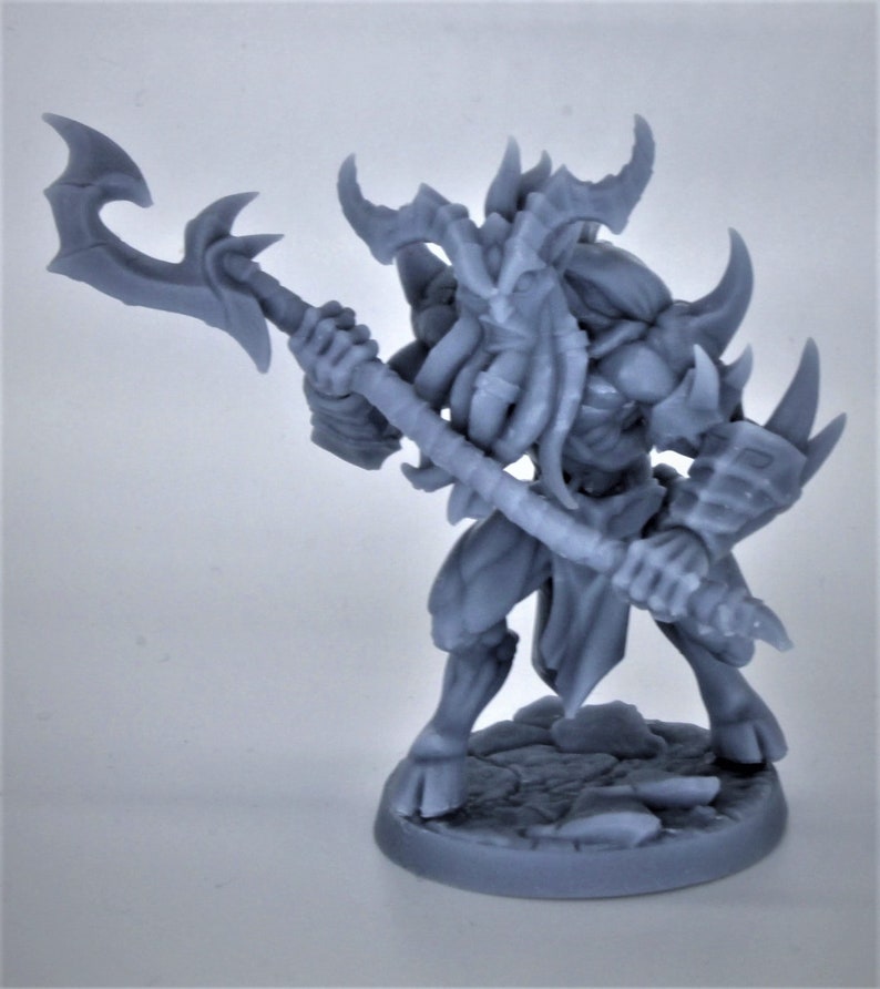 Puede incluir: Una figura en miniatura gris y detallada de una criatura con cuernos, una barba larga y un arma. La figura est&aacute; de pie sobre una base redonda.