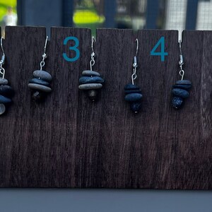 May include: Six pairs of earrings made from stacked stones in shades of gray and brown. The earrings are displayed on a wooden board with numbers 1 through 6.