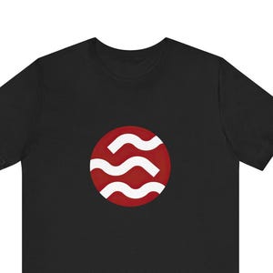 May include: Black t-shirt with a red circular emblem. The emblem features three white, wavy lines. The shirt has a crew neck and short sleeves. The design is centered.