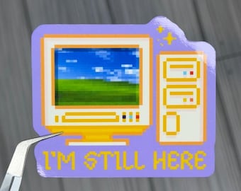 May include: A sticker featuring a pixelated computer with a Windows XP-style background of a blue sky and green field. The sticker is purple with yellow and white accents and the text "I'M STILL HERE".