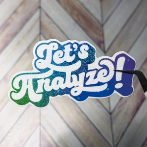Könnte beinhalten: Ein glitzernder Aufkleber mit den Worten "Let's Analyze!" in einer Retro-Schriftart. Der Text geht von Grün zu Blau über, mit einer weißen Umrandung und kleinen blauen Sternen. Der Aufkleber wird von einer schwarzen Pinzette gehalten.