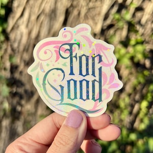 May include: A holographic sticker with a pink and green floral design and the text "For Good" in a dark blue font.