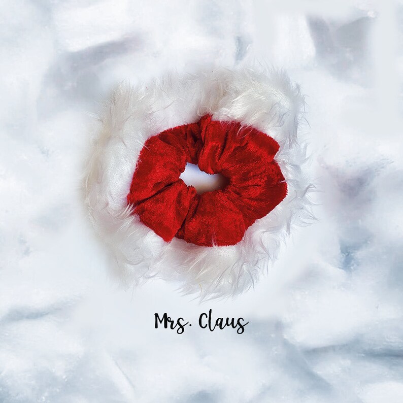 May include: Red velvet scrunchie with a white faux fur trim. The scrunchie has the text "Mrs. Claus" written below it.