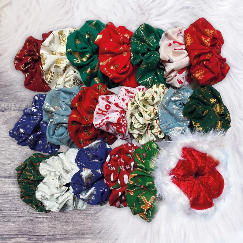 May include: A collection of 15 Christmas-themed scrunchies in various colors and patterns, including red, green, white, and gold. The scrunchies feature festive designs like snowflakes, reindeer, and Christmas trees.