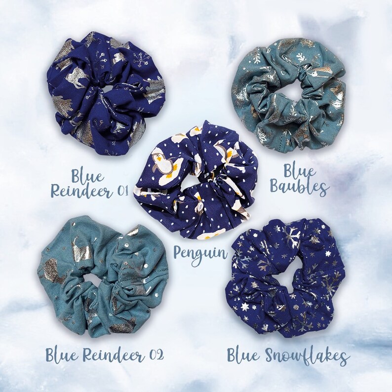 May include: Five blue and silver patterned scrunchies. The scrunchies feature different winter-themed designs, including penguins, reindeer, snowflakes, and baubles. The text "Blue Reindeer 01", "Blue Reindeer 02", "Penguin", "Blue Baubles", and "Blue Snowflakes" is printed below each scrunchie.