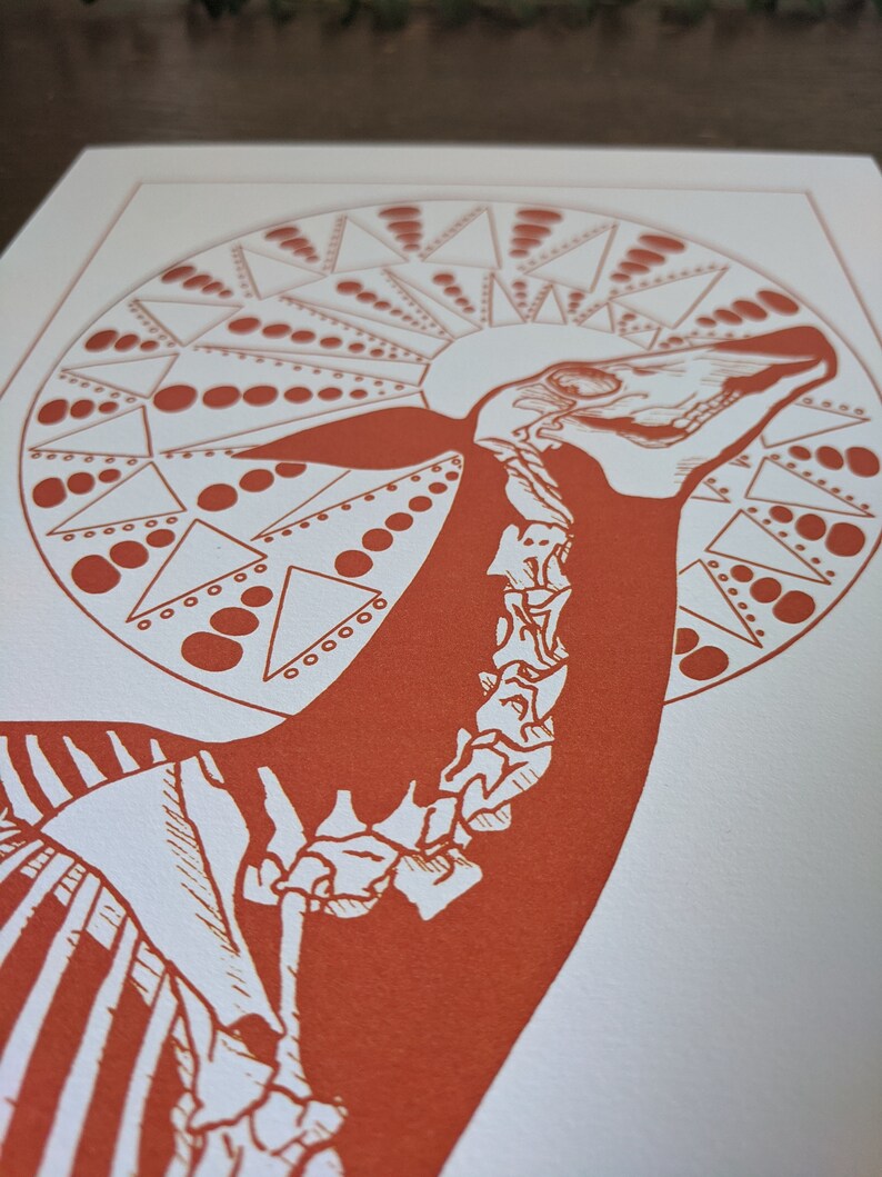 May include: A red and white print of a stylized animal skeleton with a circular design of triangles and dots around the head.