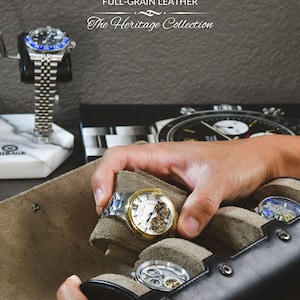 Puede incluir: Primer plano de una colecci&oacute;n de relojes, incluyendo un reloj de pulsera dorado y plateado con esfera blanca y mecanismos visibles. La imagen muestra el texto "THE MIRAGE SABLE BLACK FULL-GRAIN LEATHER The Heritage Collection". Tambi&eacute;n se ve la cita "Every watch has a story-let us take care of it for you."