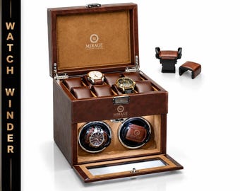 May include: A brown leather watch winder box with a hinged lid, featuring a tan interior, multiple watch pillows, and two circular winding compartments. The Mirage Luxury Travel logo is printed on the lid and front. Includes two extra watch cushions.