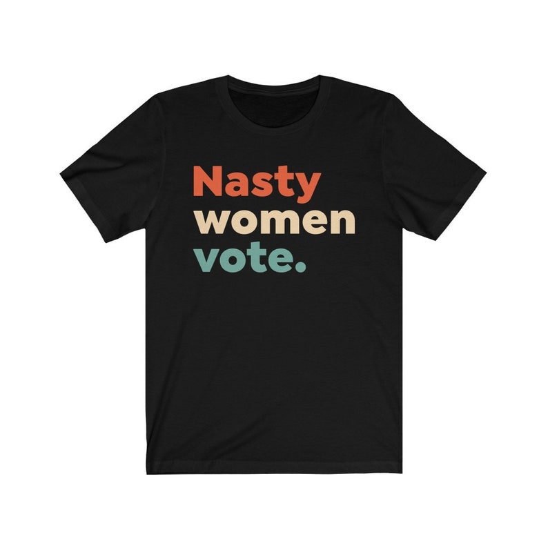 Pu&ograve; includere: Maglietta nera con il testo "Nasty women vote." in un font in stile retr&ograve; con colori rosso, arancione, giallo e blu.
