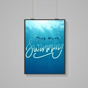 May include: A framed print with a blue underwater scene and the text "Just Keep Swimming" in white lettering.