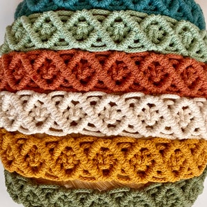 Pu&ograve; includere: Un set di sei fasce per capelli in macram&egrave; di vari colori, tra cui turchese, verde, arancione, crema, giallo senape e verde oliva. Le fasce sono realizzate con un motivo annodato e sono disposte in una pila.