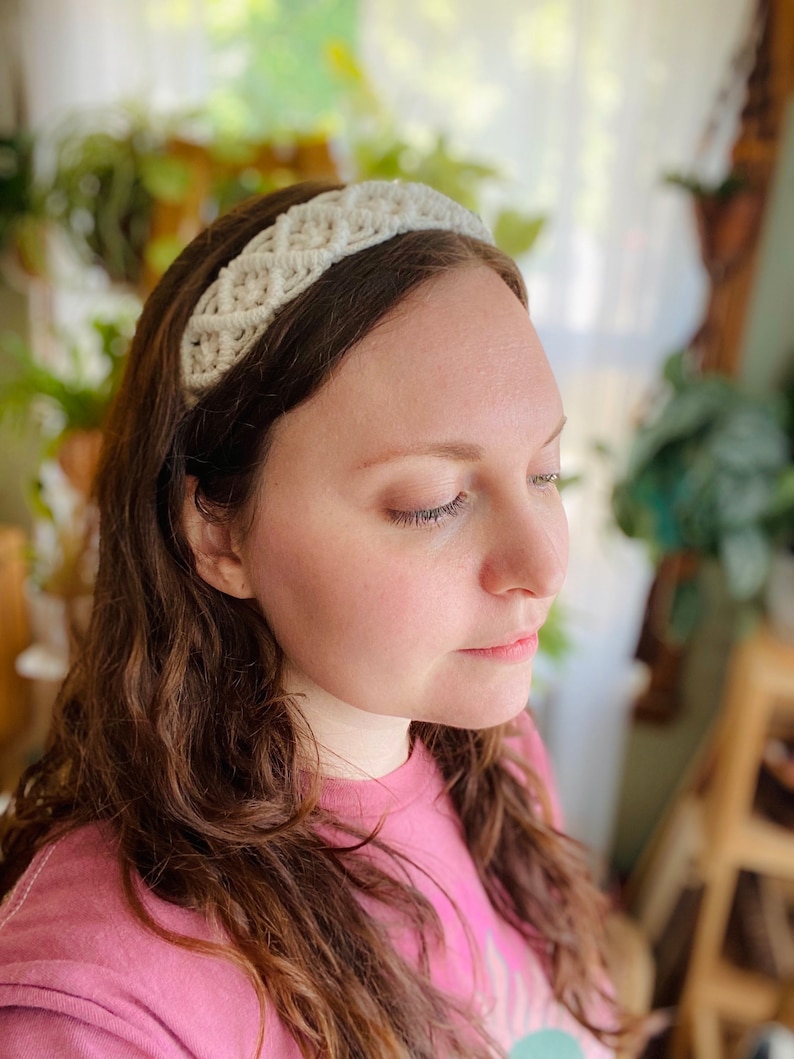Pu&ograve; includere: Un cerchietto bianco all'uncinetto con un design intrecciato. Il cerchietto &egrave; indossato da una persona con capelli lunghi e castani.
