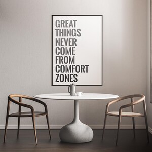 May include: A white table with two wooden chairs and a black framed poster with the text "GREAT THINGS NEVER COME FROM COMFORT ZONES".