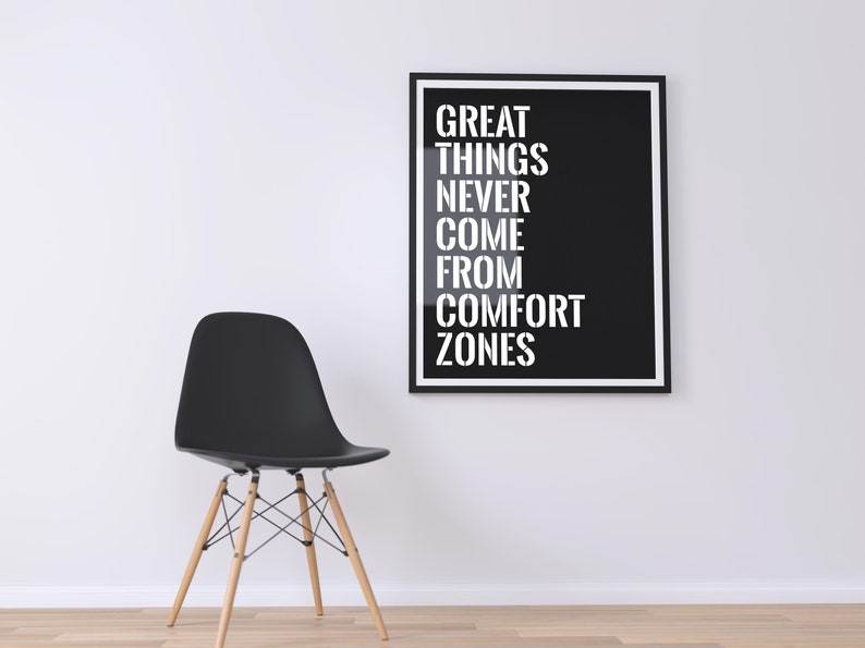 May include: A black and white motivational poster with the text "GREAT THINGS NEVER COME FROM COMFORT ZONES" hanging on a white wall above a black chair with wooden legs.