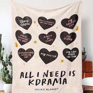 Peut inclure: Une couverture en tissu beige avec des c&oelig;urs noirs repr&eacute;sentant des titres de drames cor&eacute;ens. La couverture porte l'inscription "All I Need is Kdrama" et "Julia's Blanket".