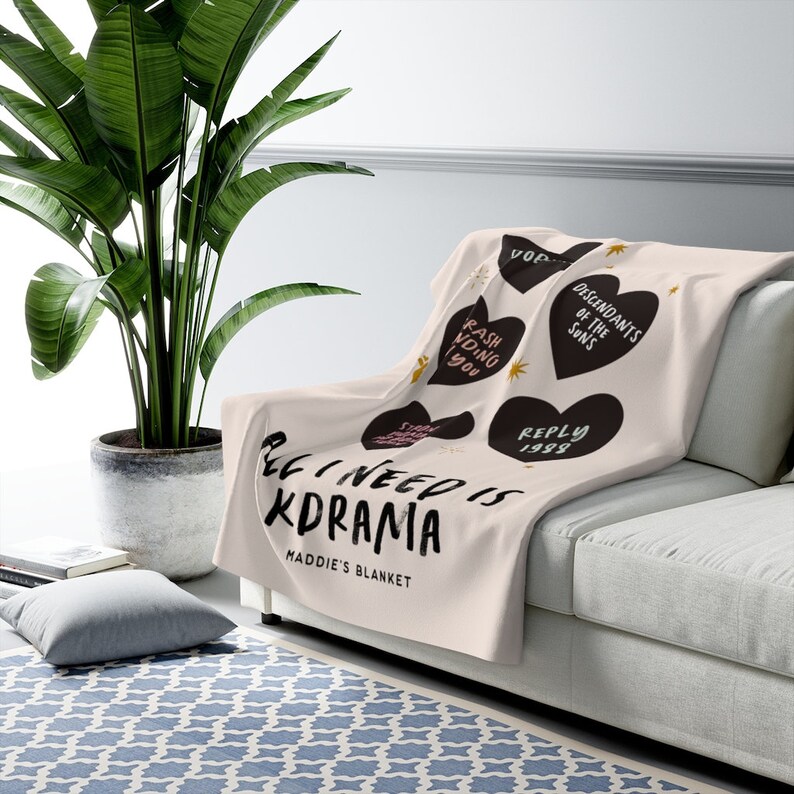 Peut inclure: Une couverture en molleton beige douce avec des c&oelig;urs noirs comportant des textes tels que "Rash Vding You", "Descendants of the Suns" et "Reply 1998". La couverture porte l'inscription "All I need is Kdrama" et "Maddie's Blanket".