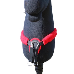 Può includere: Un cavallo a bastone nero con un'imbracatura rossa e nera. L'imbracatura ha una fodera rossa e soffice e chiusure e anelli in metallo argentato. Il cavallo è su sfondo bianco.