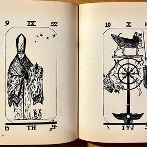 Op de afbeelding: Dubbele pagina uit een oud boek met zwart-wit illustraties van tarotkaarten. De linkerpagina toont een figuur in een gewaad met een hoge hoed, en de rechterpagina toont een gevleugeld wezen boven een wiel.