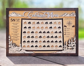 May include: Wooden framed art piece featuring the text "Colorado 14-ers" and a map of mountain peaks. The artwork includes the text "The mountains are calling and I must go" and details about the highest peak.