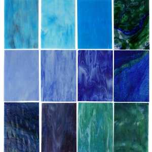 May include: A collection of rectangular stained glass sheets in various shades of blue and green. The glass has a textured, marbled appearance, with colors ranging from light sky blue to deep navy and emerald green. The sheets are arranged in a grid pattern.
