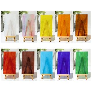 May include: Ten small canvases on easels, each displaying a different color of stained glass. The colors are white, pink, yellow, orange, brown, red, blue, purple, green, and a darker brown.