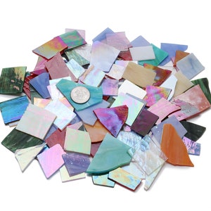 Pu&ograve; includere: Un mucchio di tessere di mosaico di vetro iridescente in vari colori, tra cui blu, verde, viola, rosa e arancio. Le tessere sono di forma e dimensioni irregolari, e alcune hanno un bagliore metallico.