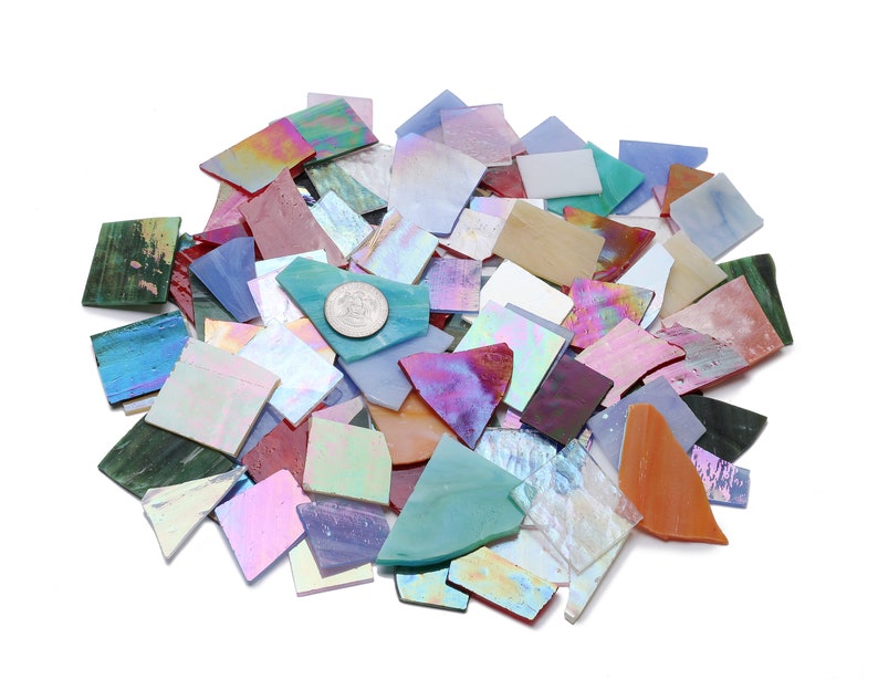 Pu&ograve; includere: Un mucchio di tessere di mosaico di vetro iridescente in vari colori, tra cui blu, verde, viola, rosa e arancio. Le tessere sono di forma e dimensioni irregolari, e alcune hanno un bagliore metallico.