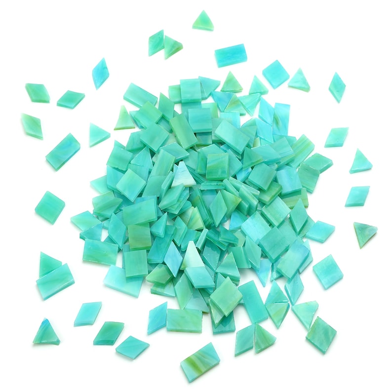 May include: A large pile of turquoise blue glass mosaic tiles in various shapes, including squares and triangles, scattered on a white background.