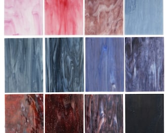 Op de afbeelding: Een verzameling van twaalf rechthoekige glas-in-loodplaten in verschillende kleuren. De kleuren zijn onder meer roze, rood, bruin, blauw en zwart. Elke plaat heeft een uniek gemarmerd of gestreept patroon, wat een textuur geeft. Ideaal voor knutselprojecten.