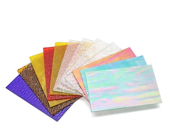 May include: Assortment of colorful textured glass sheets in various shades of purple, brown, orange, red, pink, blue, and white. The sheets are arranged in a fan shape.