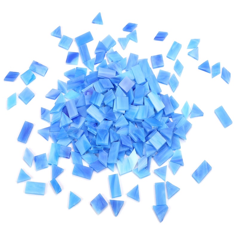 May include: A large pile of light blue glass mosaic tiles in various shapes, including squares and triangles. The tiles are scattered on a white background.