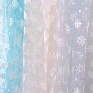 May include: Three sheer fabric panels with a snowflake pattern. The panels are in shades of blue, white, and light blue.